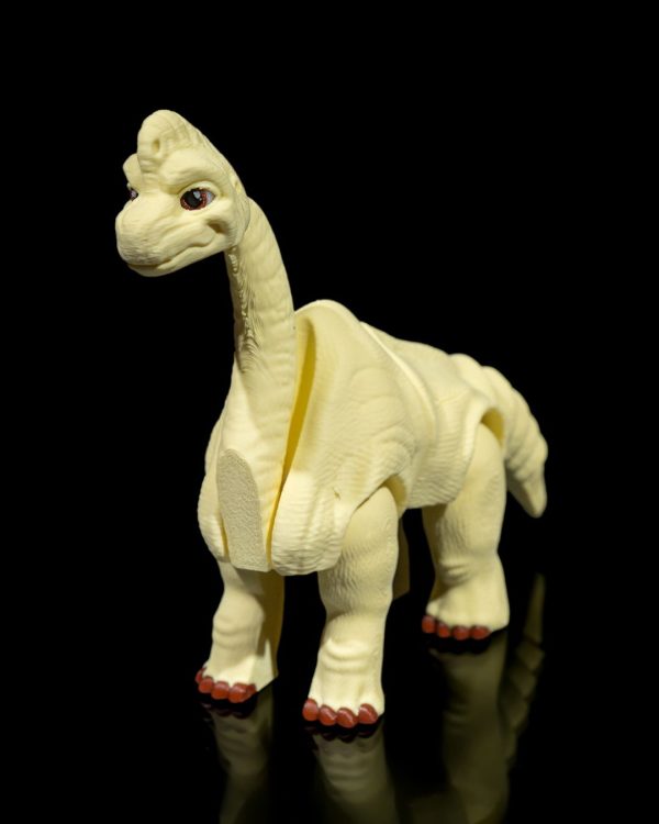 Articulated 3D-printed Brachiosaurus figure in a beige color with movable limbs, displayed against a black background.