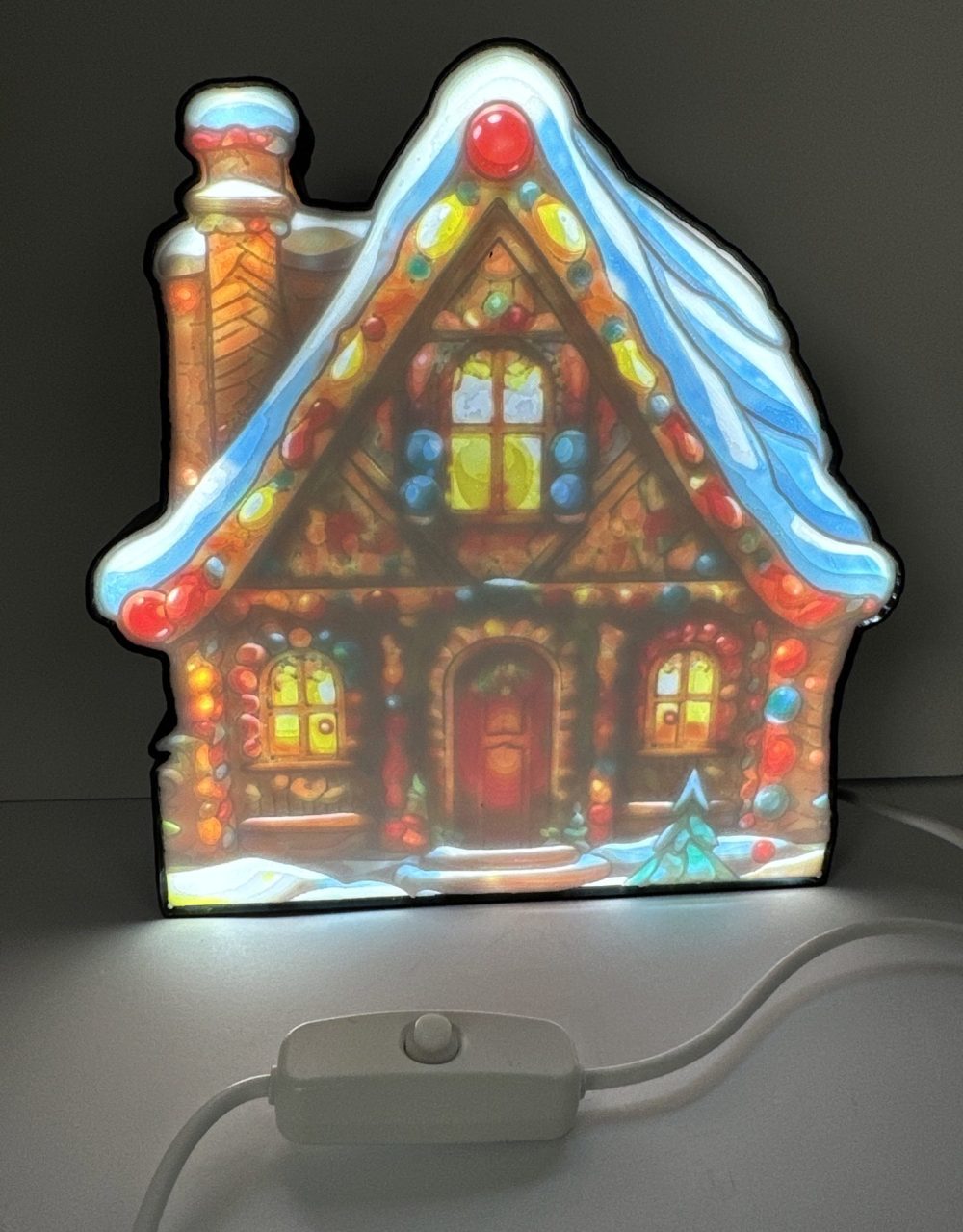 Illuminated gingerbread house LED light with vibrant colors and detailed candy decorations.